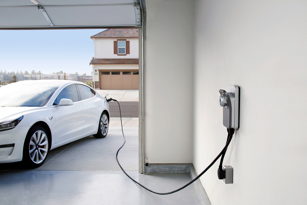 In Vancouver, WA, a white electric car is parked in a garage, connected to a home EV charging station. The setup highlights the convenience of professional electrician services for installing efficient home charging solutions.